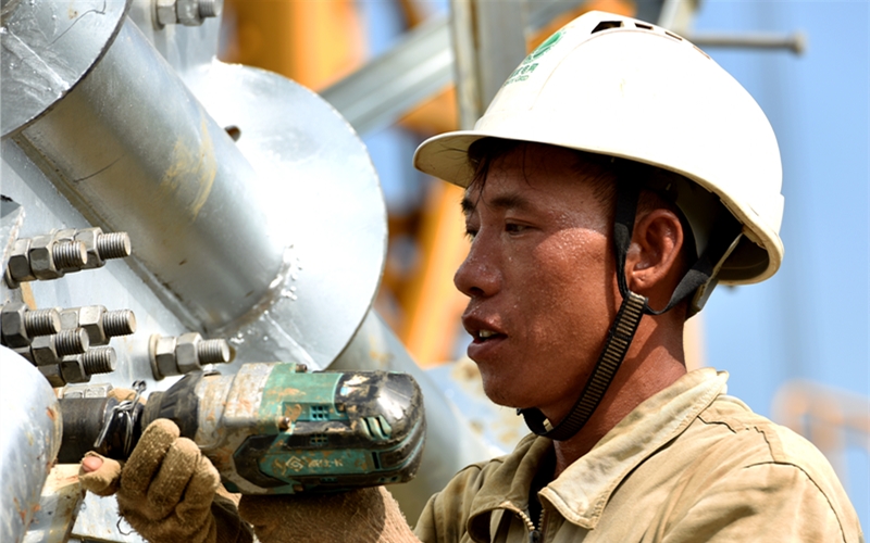 國網(wǎng)湖北送變電工程有限公司施工人員頭頂烈日，用電動扳手緊固螺栓。鄒小民攝