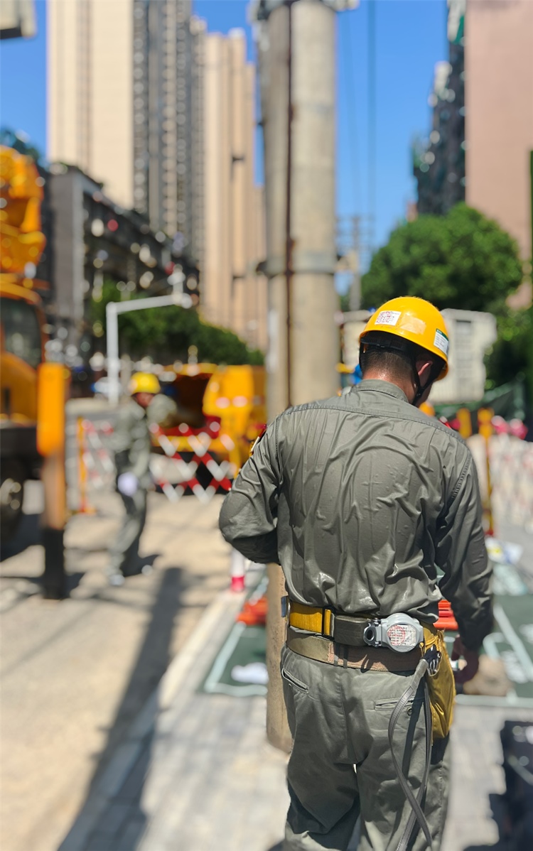 電力工作人員穿著特殊材質(zhì)的絕緣披肩，其厚度相當(dāng)于5件厚雨衣。王欣攝