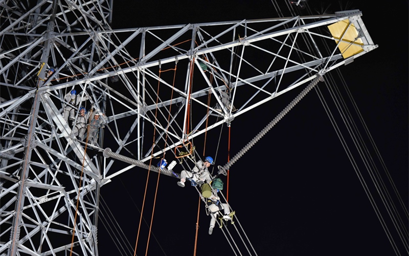在500千伏泉孝線53號塔位，送變電公司多名高空作業(yè)人員利用夜間開展施工。鄒小民攝