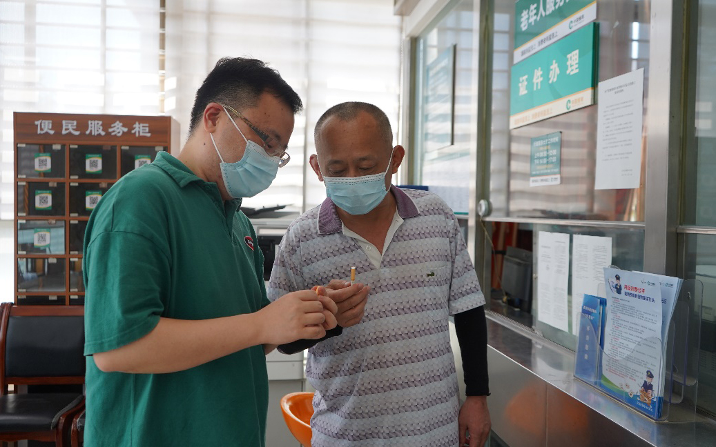 工作人員(左)為群眾介紹真假煙鑒別技巧。