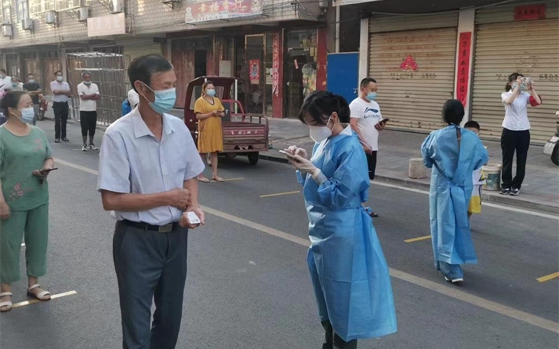 下沉社區(qū)的紀(jì)檢監(jiān)察干部正在幫助居民在手機(jī)上申請健康碼