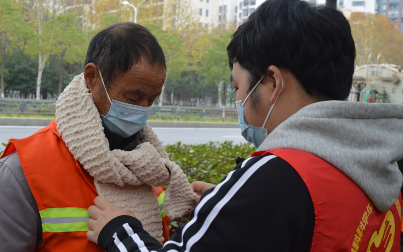 志愿者給環(huán)衛(wèi)工人戴圍巾。