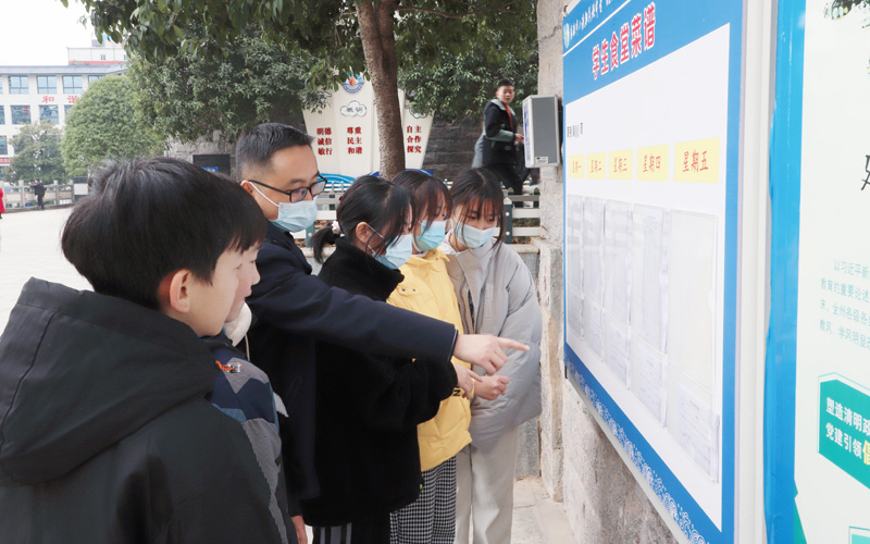 師生一起觀看學(xué)校食堂收支明細(xì)公示欄。