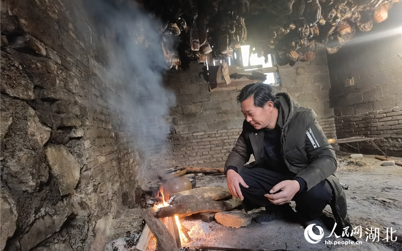 孫宜宗正在生火烤制熏肉。人民網(wǎng) 周雯攝