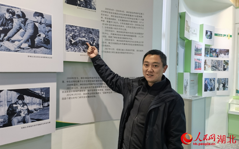 黃天鵬指著展板中懸掛的圖片向記者介紹，他們當(dāng)時去野外考察留下的珍貴照片。人民網(wǎng)周雯攝