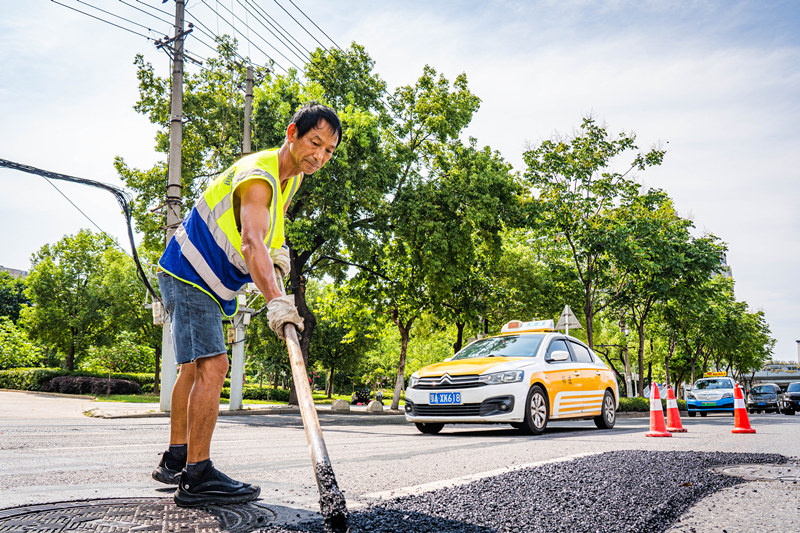 烈日下，武漢市市政維修人員對(duì)路面局部破損的位置鋪設(shè)瀝青混凝土面層。詹重山攝