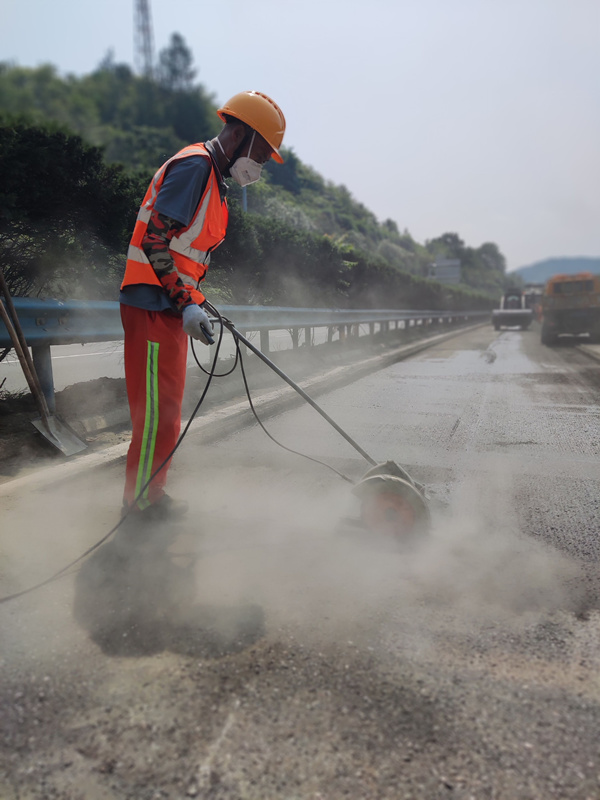 在福銀高速十土路段“集約化養(yǎng)護”施工現(xiàn)場，湖北交投鄂西北運營公司施工人員冒著高溫切割路面坑槽。金偉忠攝