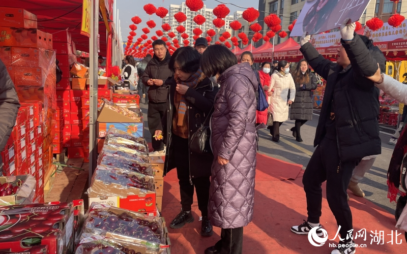 前來打年貨的市民在攤位前品嘗車?yán)遄?。人民網(wǎng)記者 周恬攝