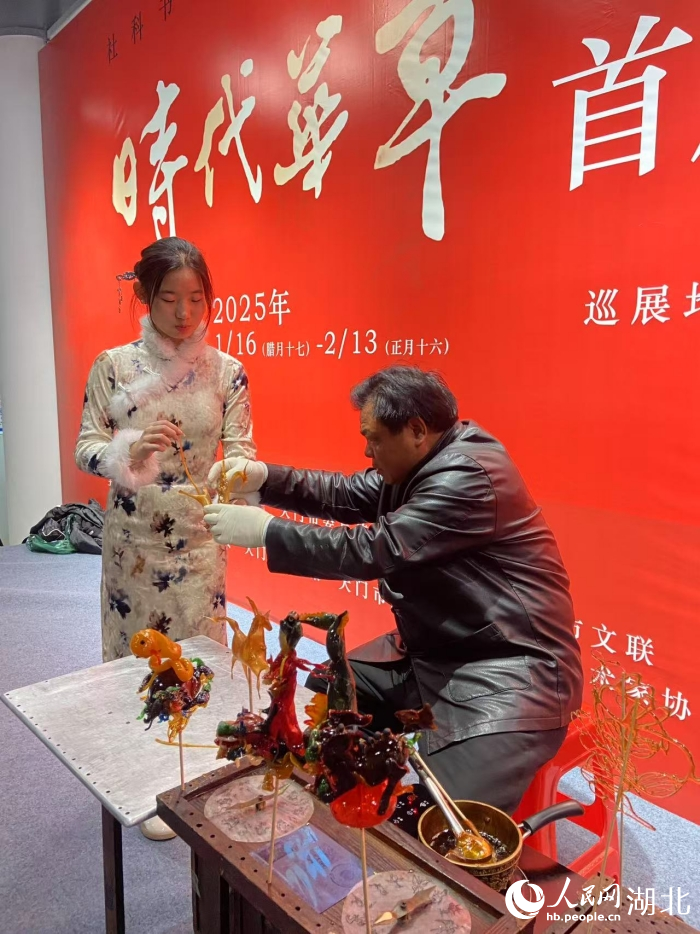 范耀堂在展會(huì)上和游客互動(dòng)吹糖人。人民網(wǎng)記者 張雋攝