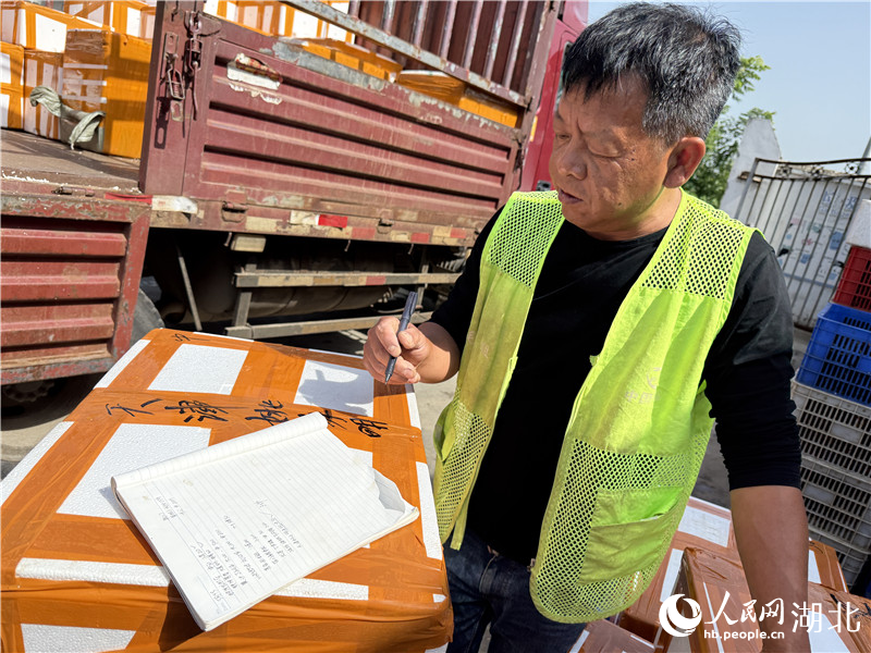 “中國(guó)蝦谷”收貨組的工作人員正在給打包好的小龍蝦做標(biāo)記。人民網(wǎng)記者張雋攝