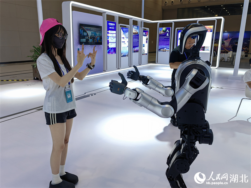 參會嘉賓與服務外包企業(yè)帶來的人形機器人互動。人民網(wǎng)記者 郭婷婷攝