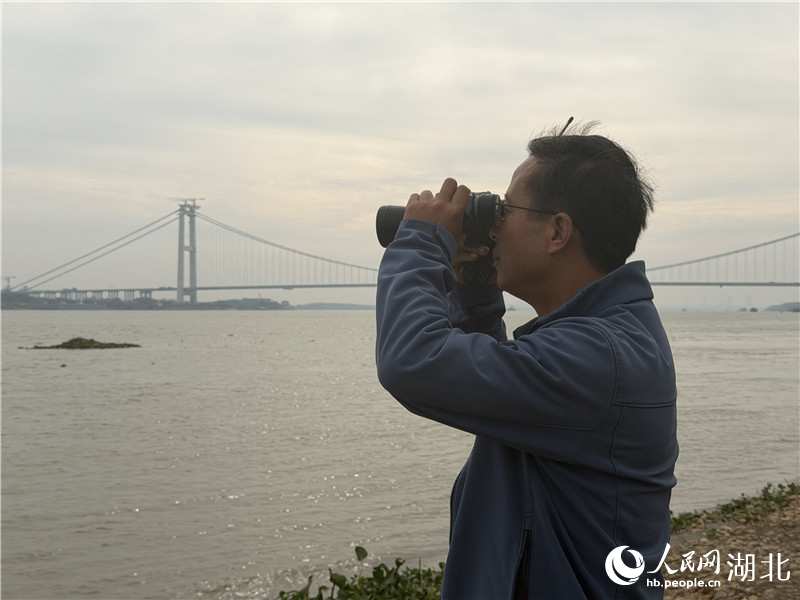 徐建利在江邊觀測江豚。人民網(wǎng)記者 張沛攝