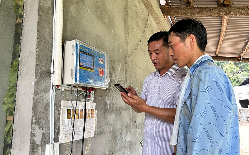 技術(shù)員指導(dǎo)煙農(nóng)在手機(jī)查看煙葉烘烤狀態(tài)。楊威攝